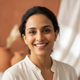 Close-up portrait of a smiling South Asian woman in her late 30s, looking happy and satisfied.